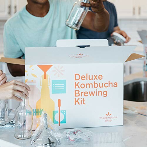 People using a deluxe kombucha brewing kit in a kitchen.